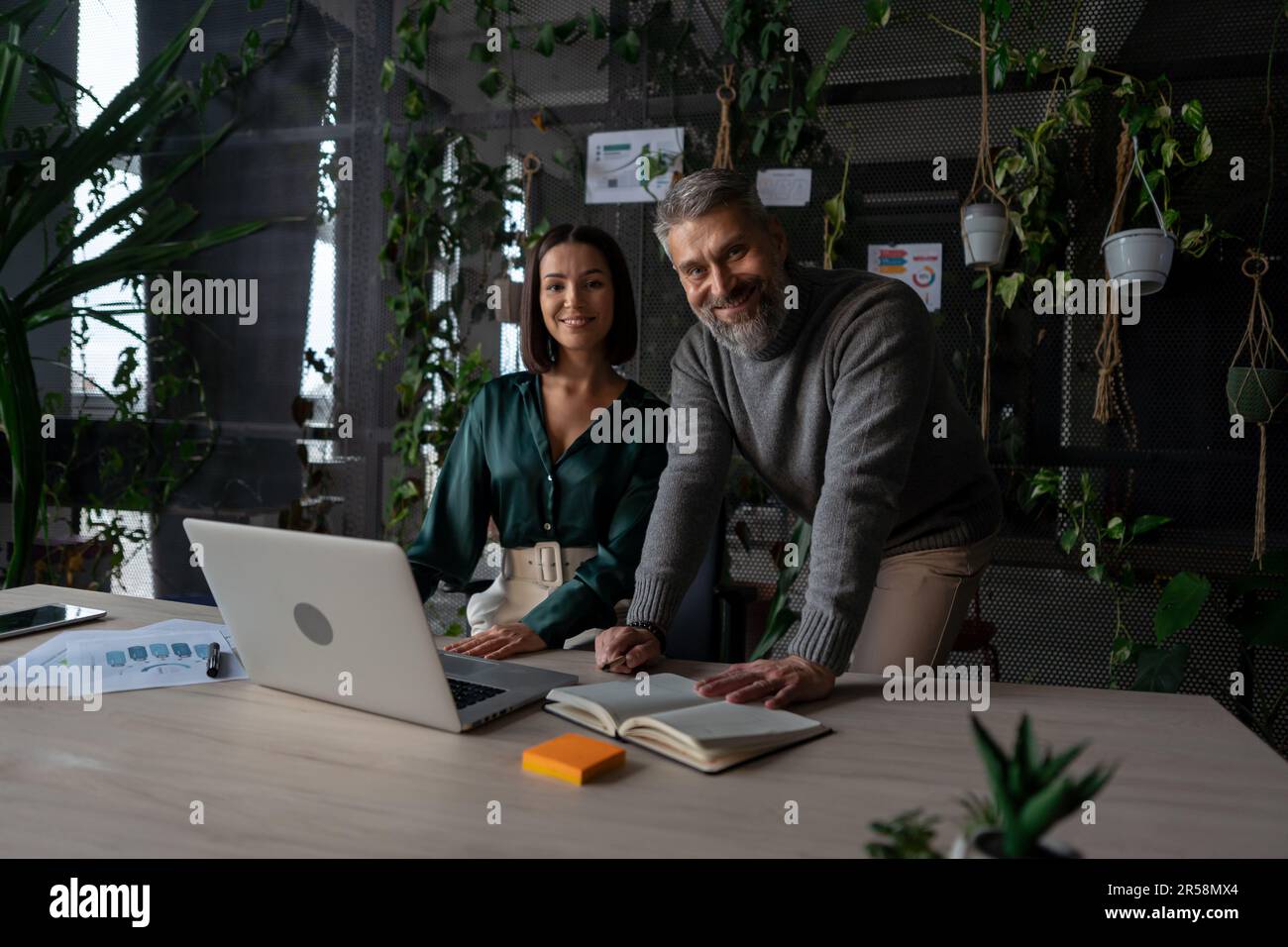 Young manager talking with experienced colleague while using laptop computer in office Stock Photo
