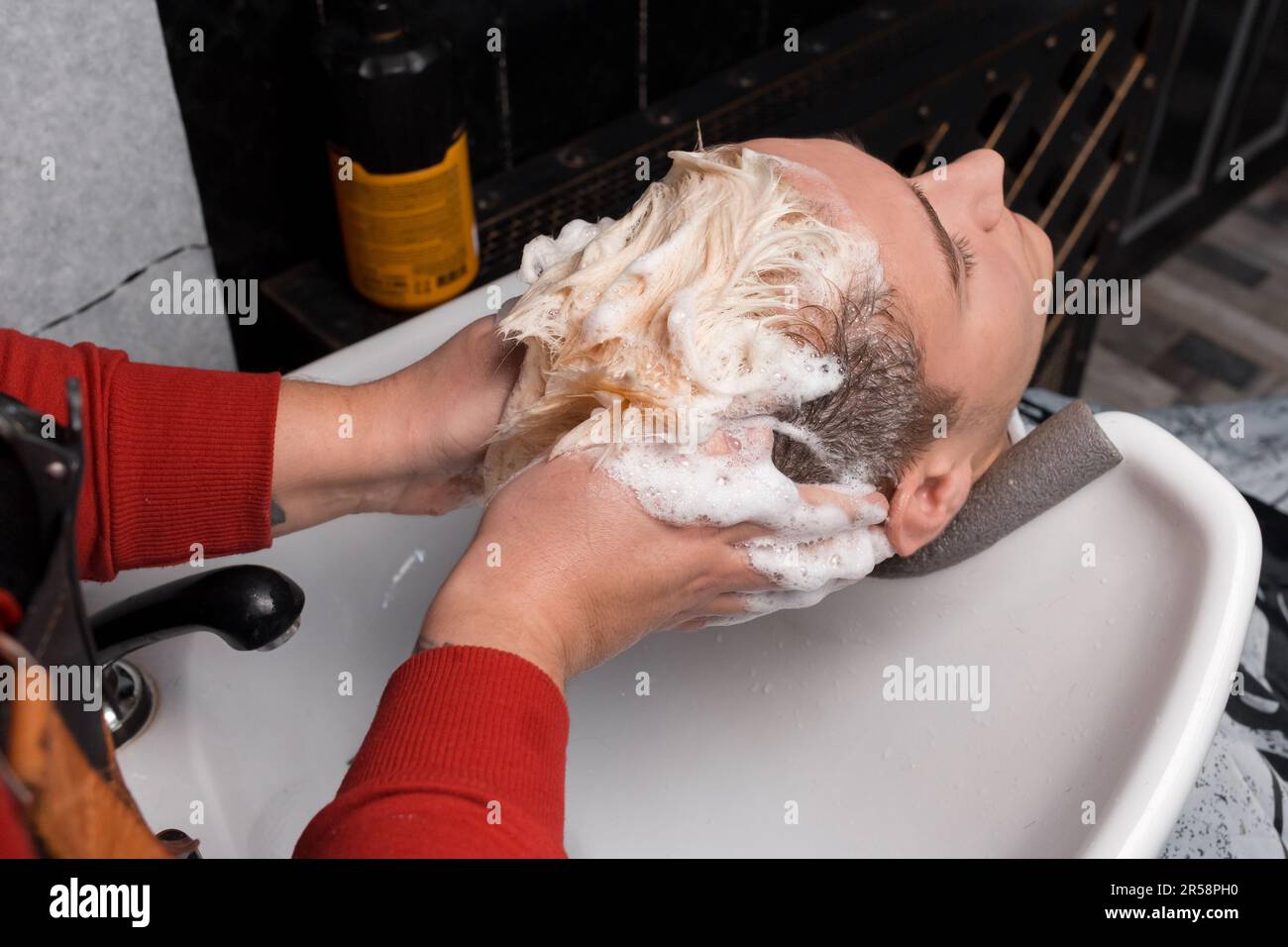 The hands of a professional hairdresser wash and massage the client's