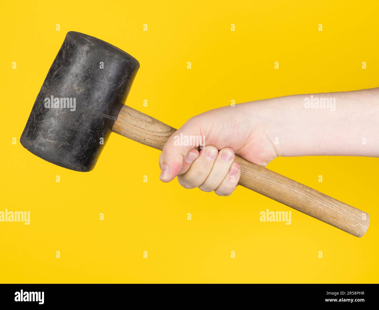 Hand with big hammer, yellow background. no face. Concept, studio. Stock Photo