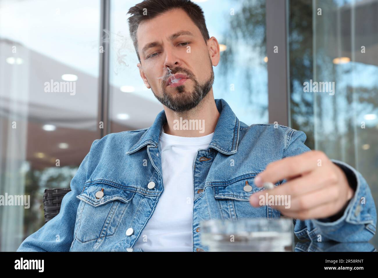 Handsome man smoking cigarette in outdoor cafe Stock Photo