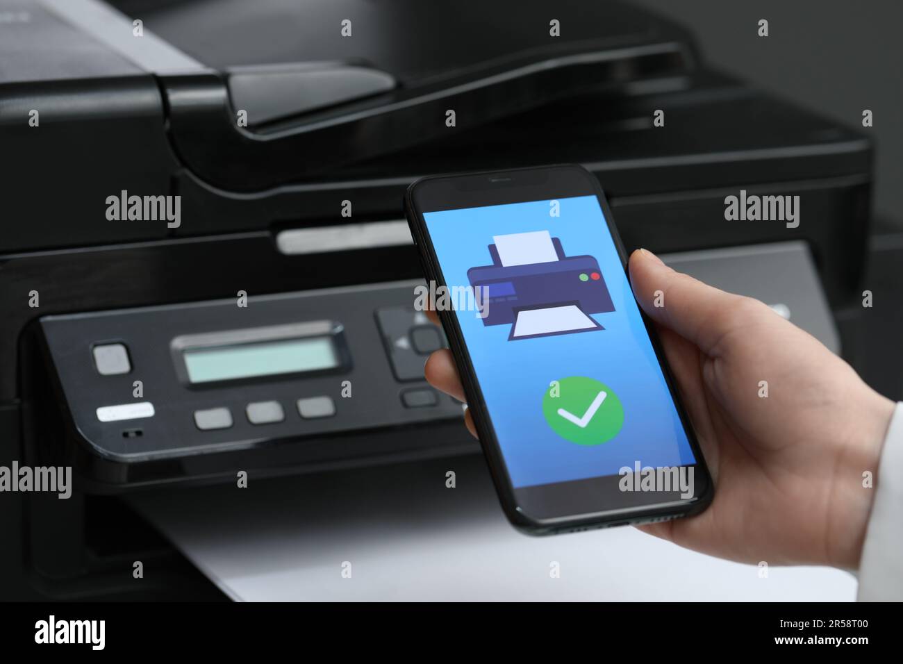 Man using printer management application on mobile phone indoors, closeup Stock Photo