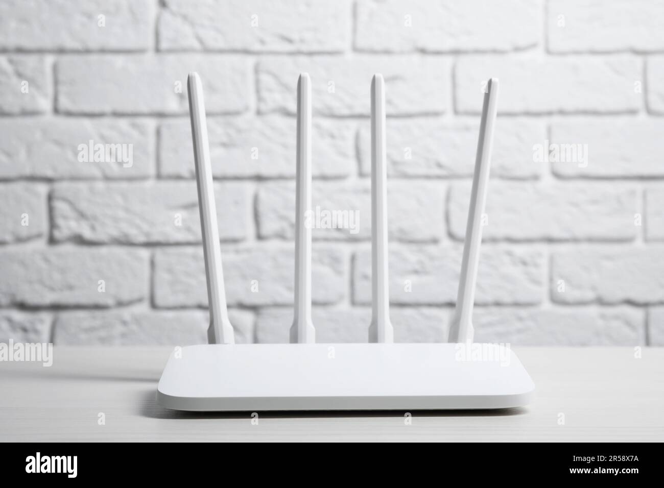 New Wi-Fi router on white wooden table against brick wall Stock Photo ...