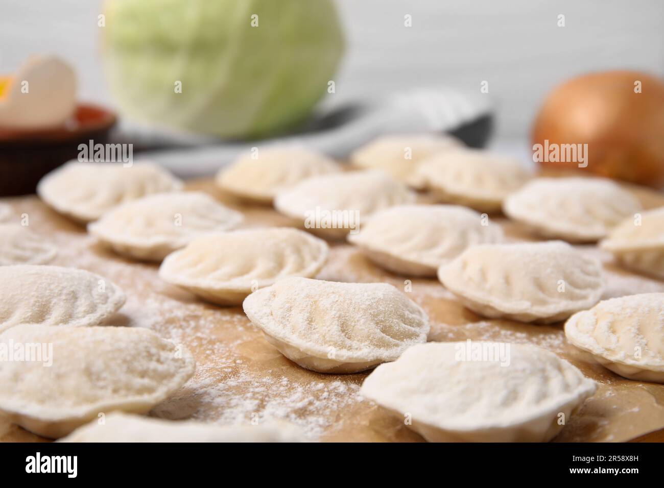 Raw dumplings (varenyky) with tasty filling and flour on parchment