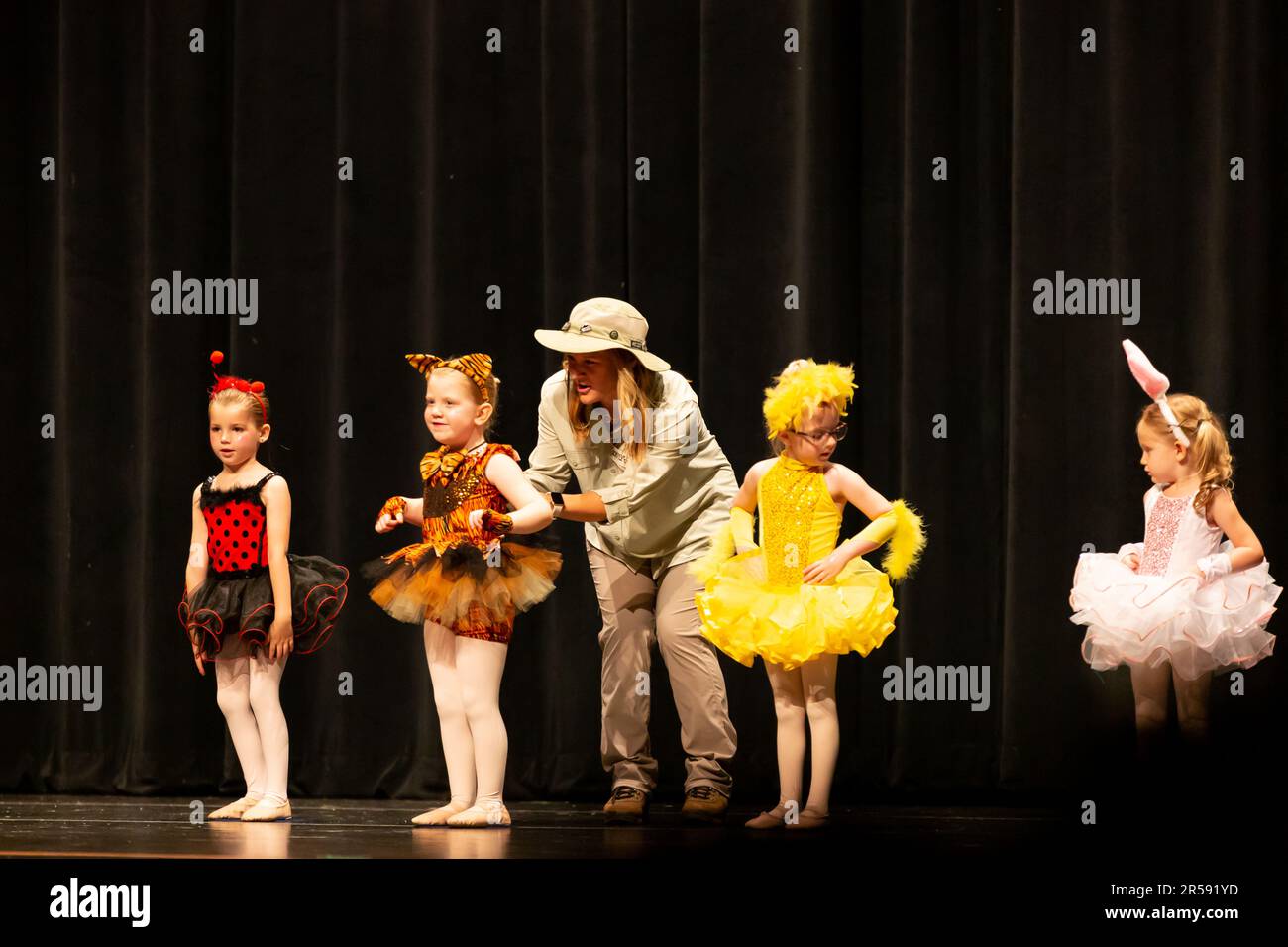 Little girls perform a dance routine with help from an instructor. Stock Photo