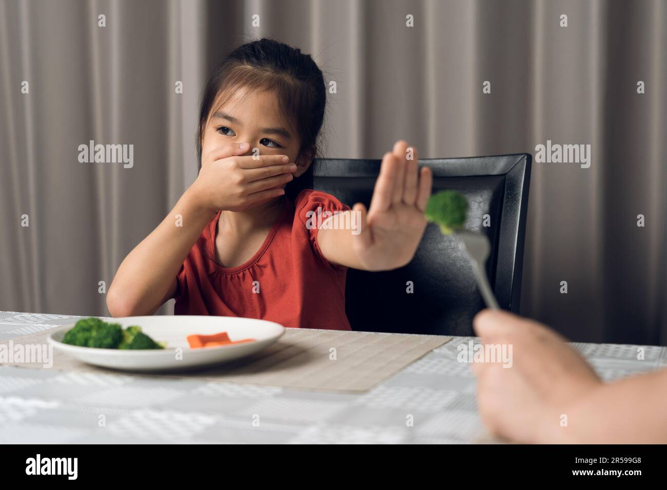 Little cute kid girl refusing to eat healthy vegetables. Children do not like to eat vegetables
