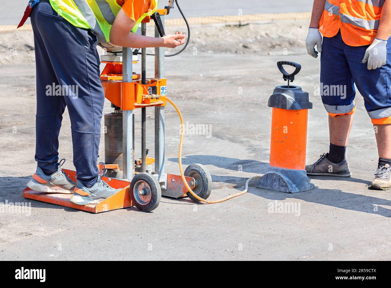 Road builders set up a gasoline drilling machine to cut asphalt concrete samples on a sunny day. Stock Photo