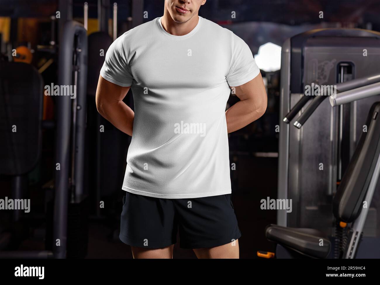 White sports t-shirt mockup on a sports guy with hands behind his back, shirt on an athlete in the gym, front view. Apparel template on inventory back Stock Photo