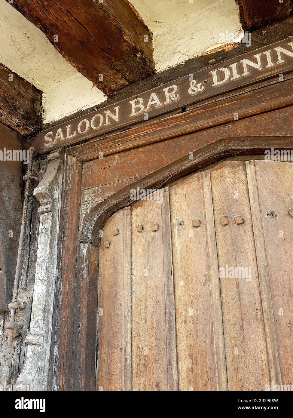 Detail of an old studded wooden door with sign on a traditional historic building in Saffron Walden, UK. Stock Photo