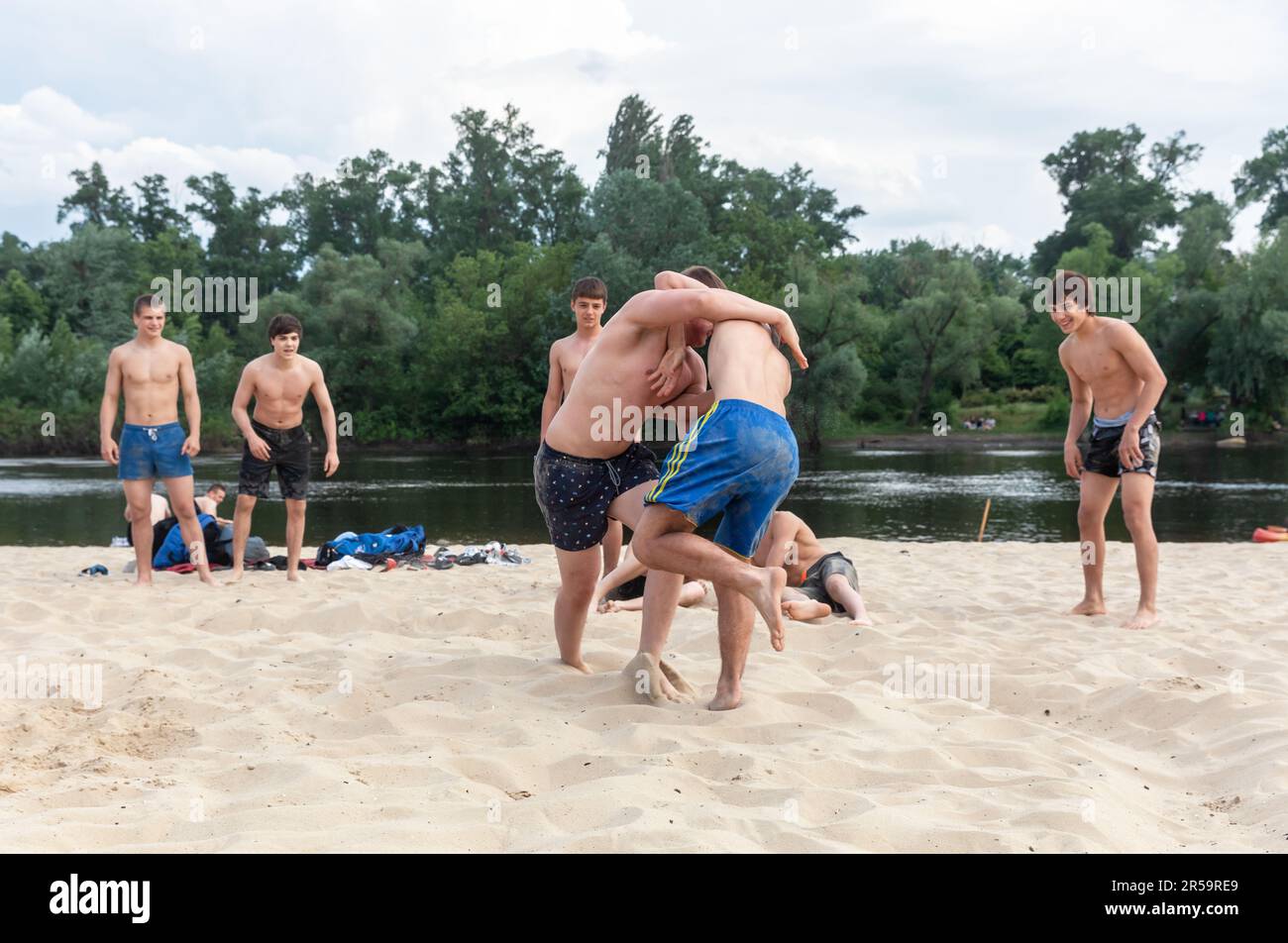 KYIV, UKRAINE - May. 27, 2023: Teenagers relax and have fun in beach wrestling on the city beach in Kiev despite the daily missile attacks on the Ukrainian capital. Stock Photo