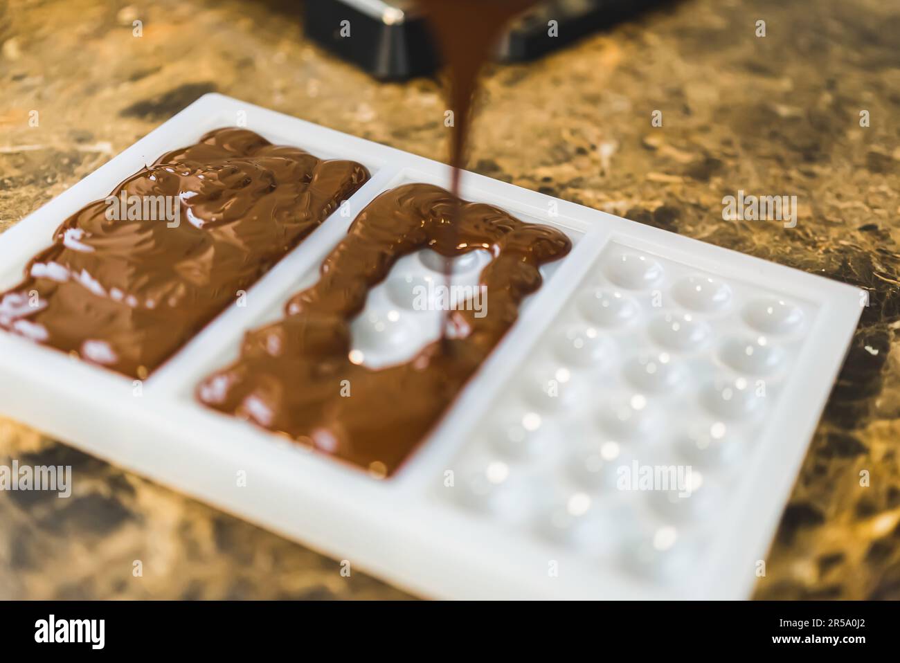 chocolatier pouring caramel filling into chocolate mold preparing handmade  candy Stock Photo - Alamy