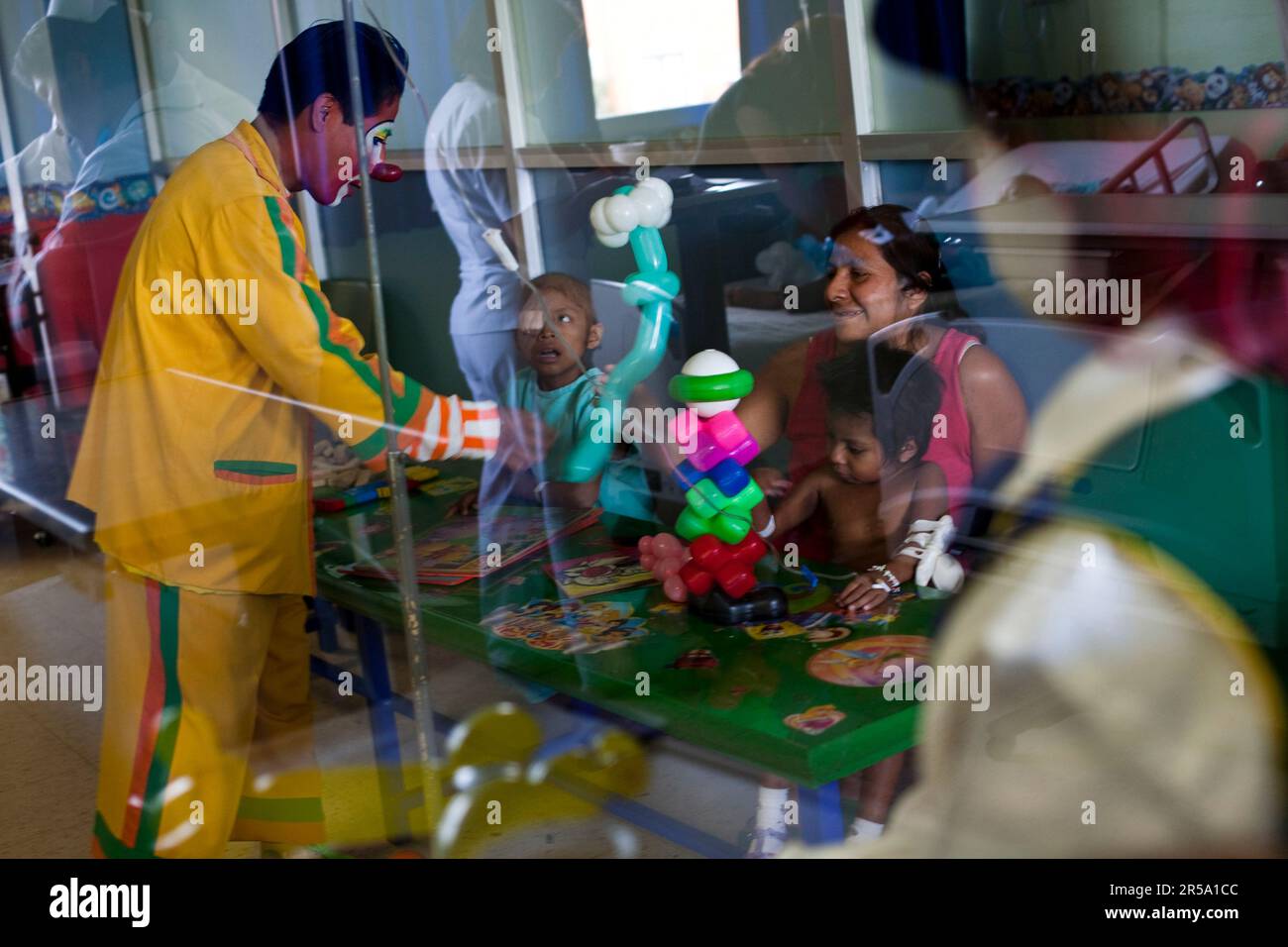 An evangelical Christian clown offers a balloon to a child with leukemia at a hospital in Oaxaca, Mexico. Stock Photo