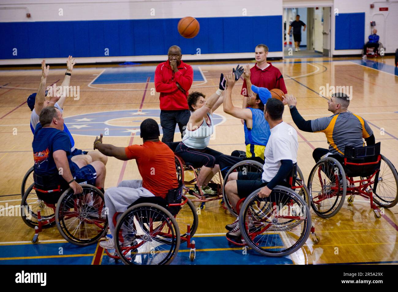 A coach watches over a wheelchair basketball scrimmage during