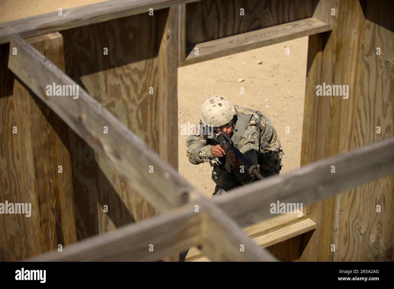 A soldier basic training moves tactically past a window during close quarters combat training. Stock Photo