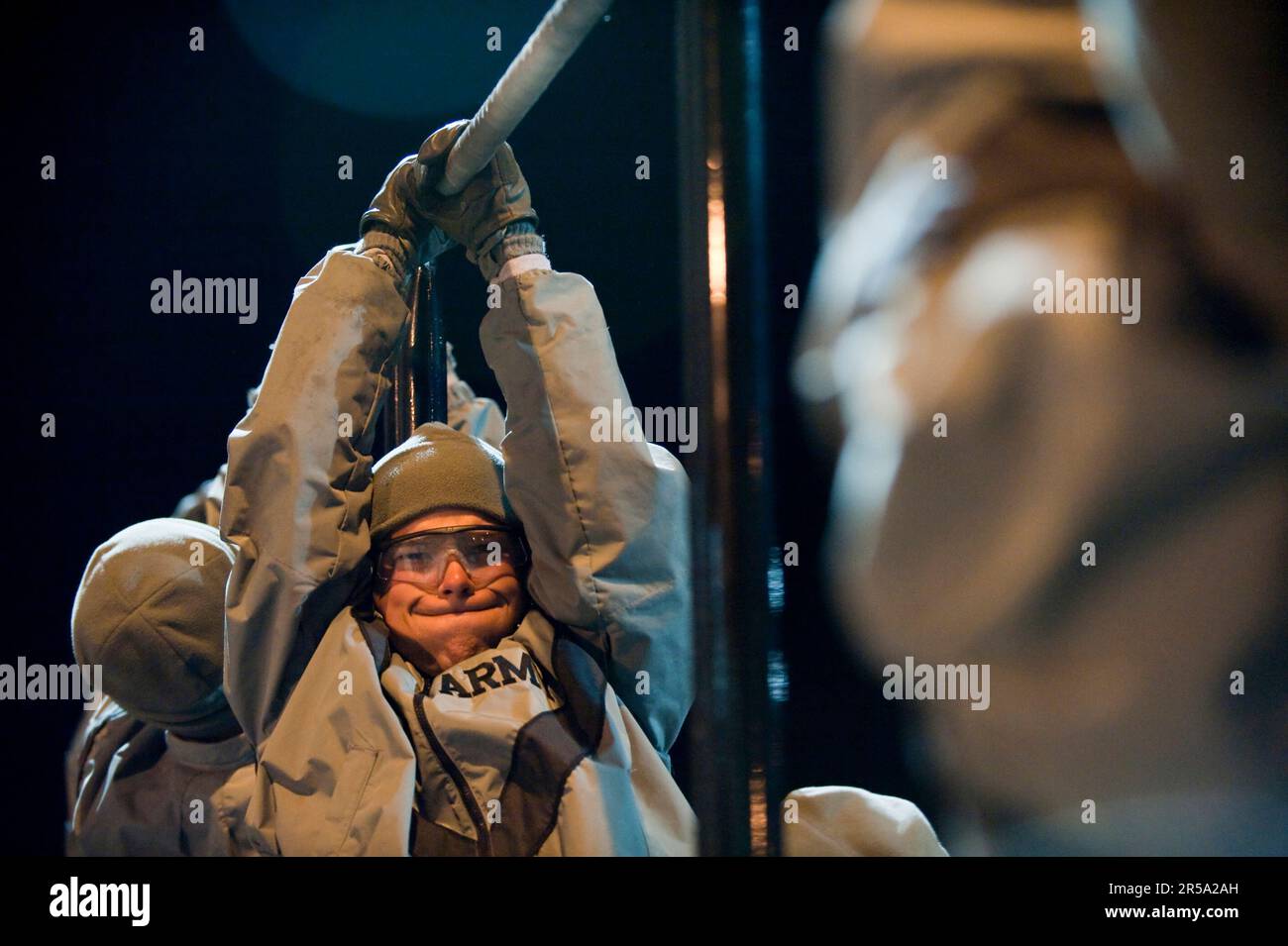 A soldier in basic training does chin-ups from a high bar during the physical training formation. Stock Photo