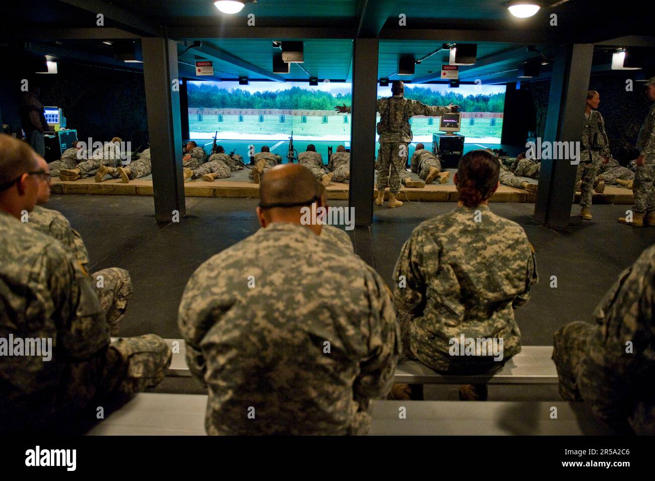 A drill sergeant talks to soldiers in training about proper indoor range etiquette during their preliminary weapons training course. Stock Photo