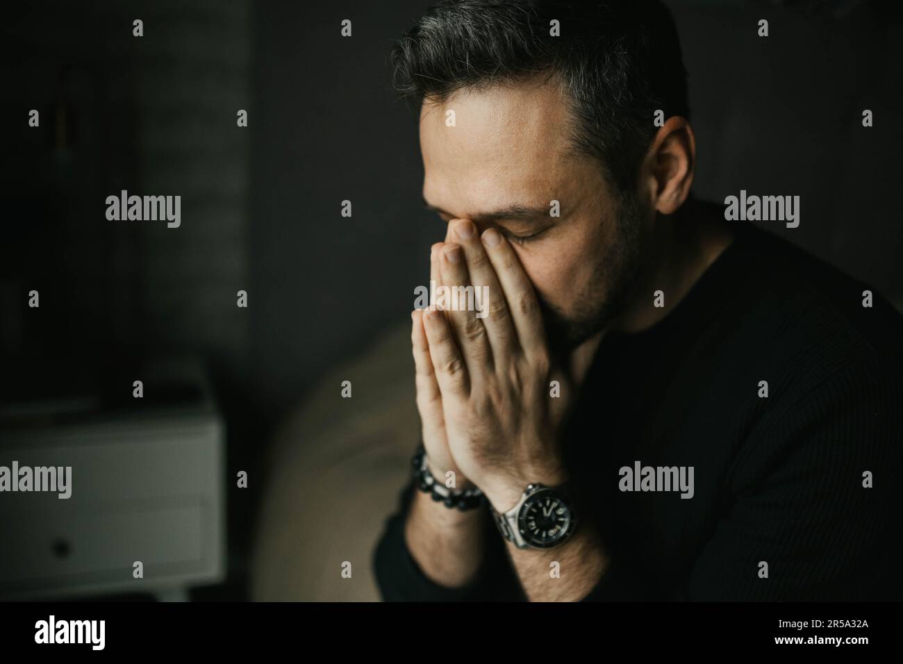 Sad man put his hands to his face sitting on the bed Stock Photo
