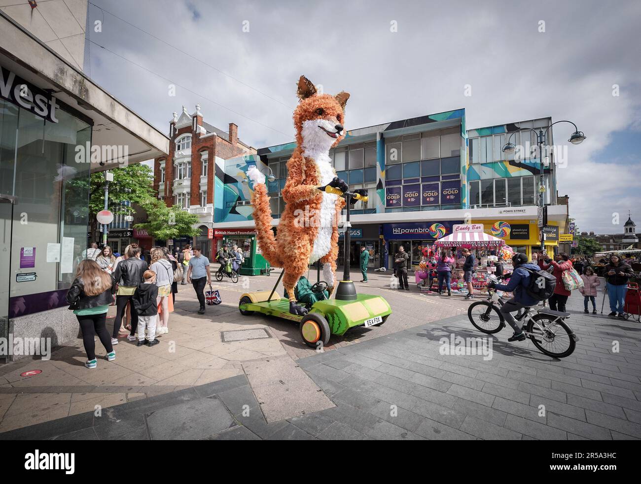 London, UK. 2nd June 2023. Farrah the Fox, a five-metre tall puppet on a giant scooter, sets off in Woolwich to celebrate England’s high streets this summer. Part of Hi! Street Fest by Historic England, a landmark nation-wide commission with Emergency Exit Arts bringing people together to celebrate what’s special about our high streets. Credit: Guy Corbishley/Alamy Live News Stock Photo
