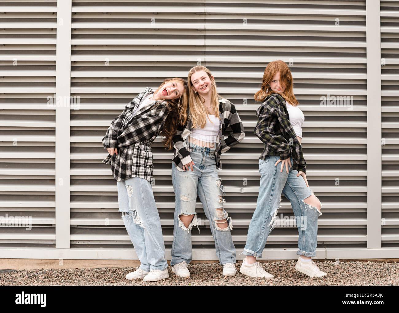 Three happy teen girls posing in front of strong vertical lines. Stock Photo