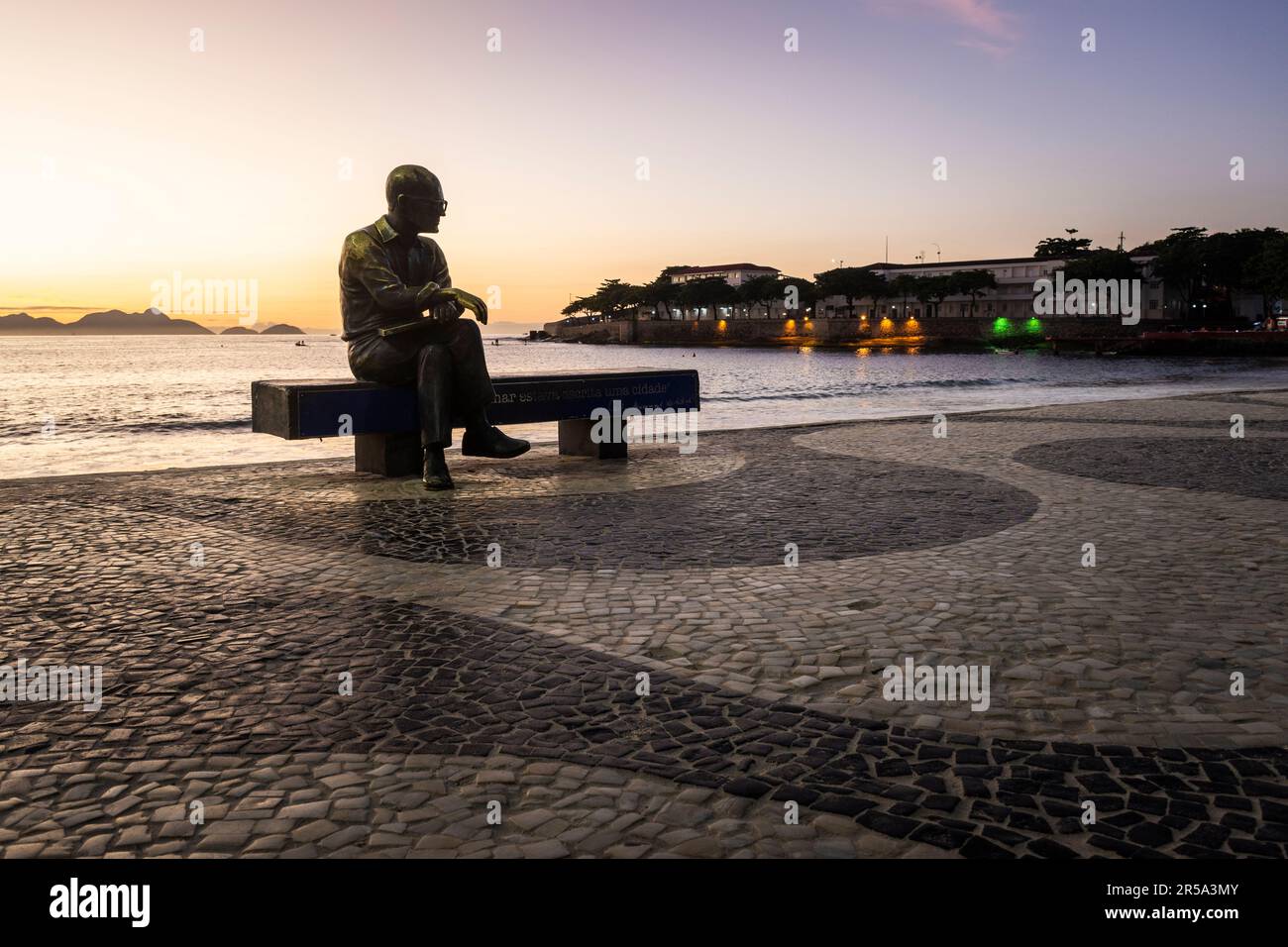 Beautiful sunrise view to poet statue sitting on beach bench Stock Photo