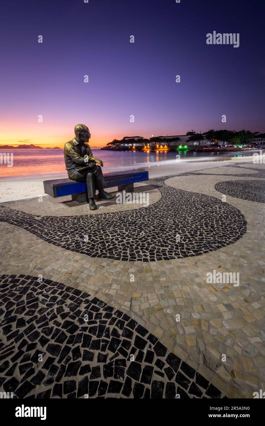 Beautiful sunrise view to poet statue sitting on beach bench Stock Photo