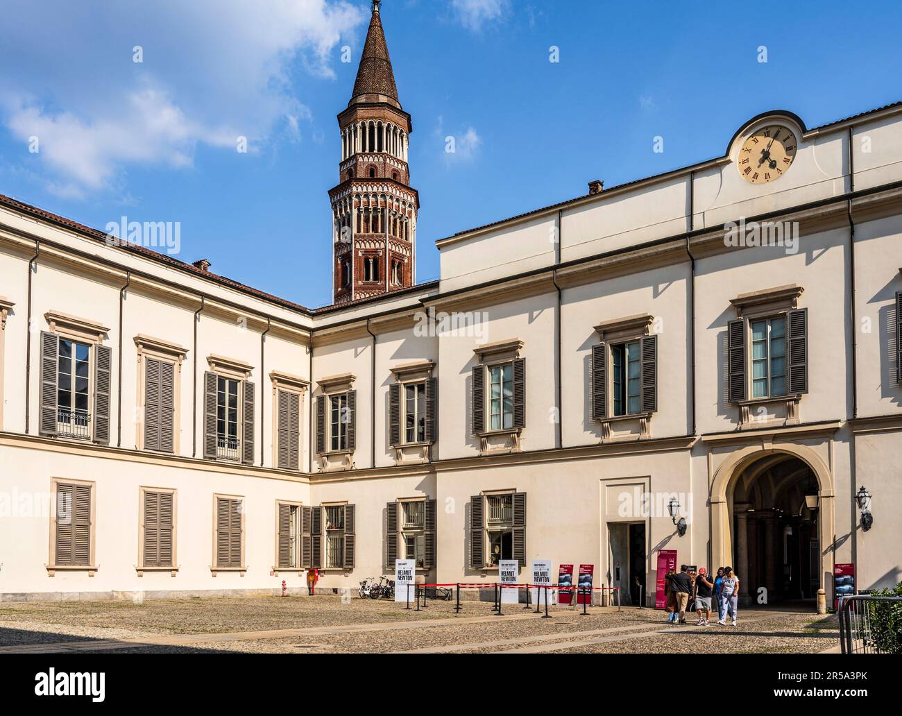 The courtyard of Palazzo Reale ('Royal Palace') with tourists and the tower of San Gottardo in Corte church, in Milano city center, Italy Stock Photo