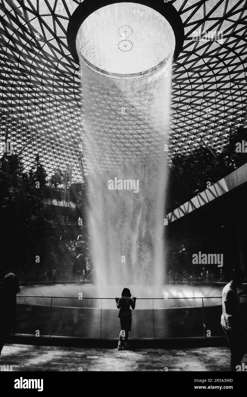 Girl stands in front of waterfall coming from the ceiling Stock Photo