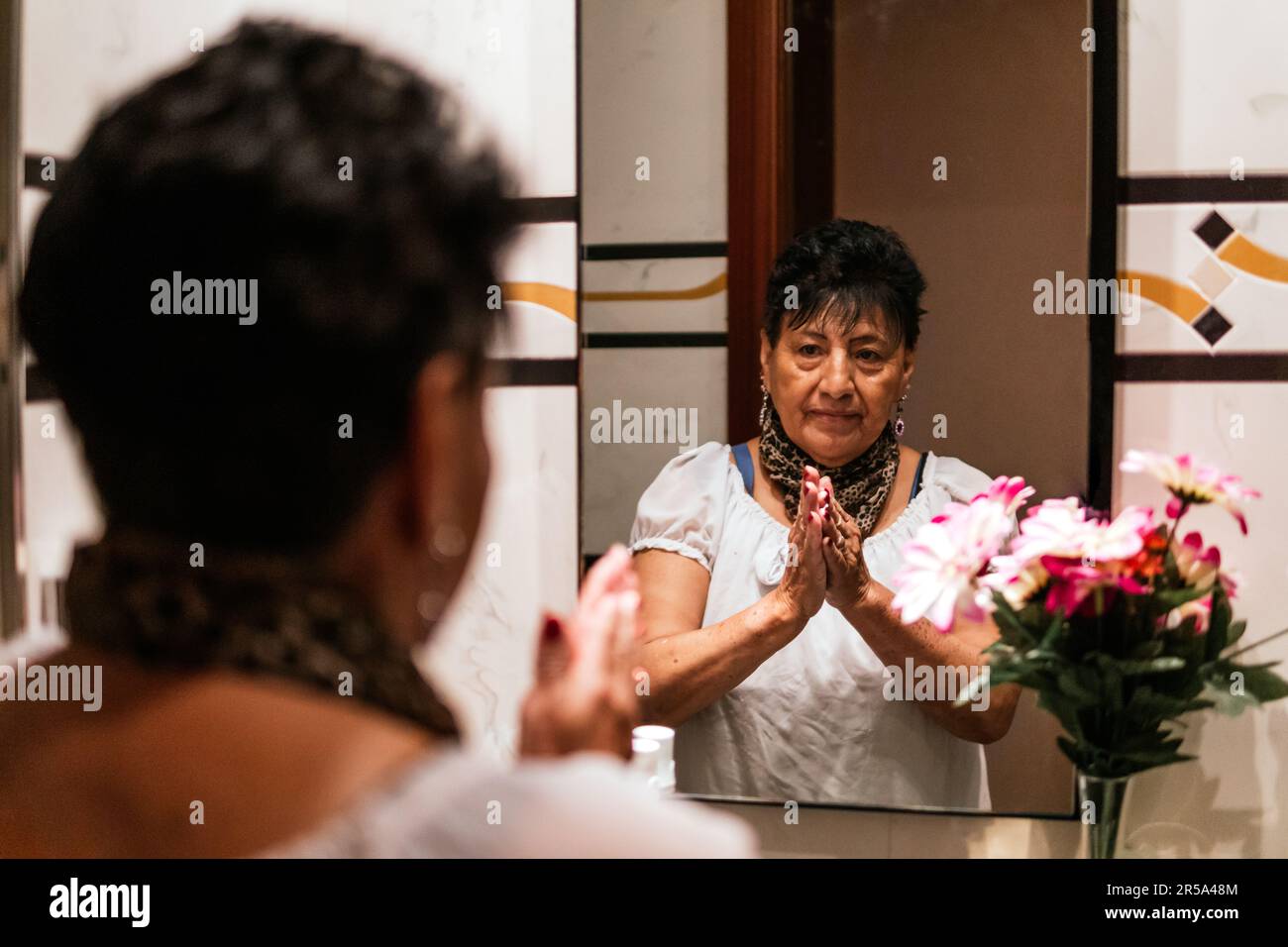 older latin american woman putting cream on her face Stock Photo