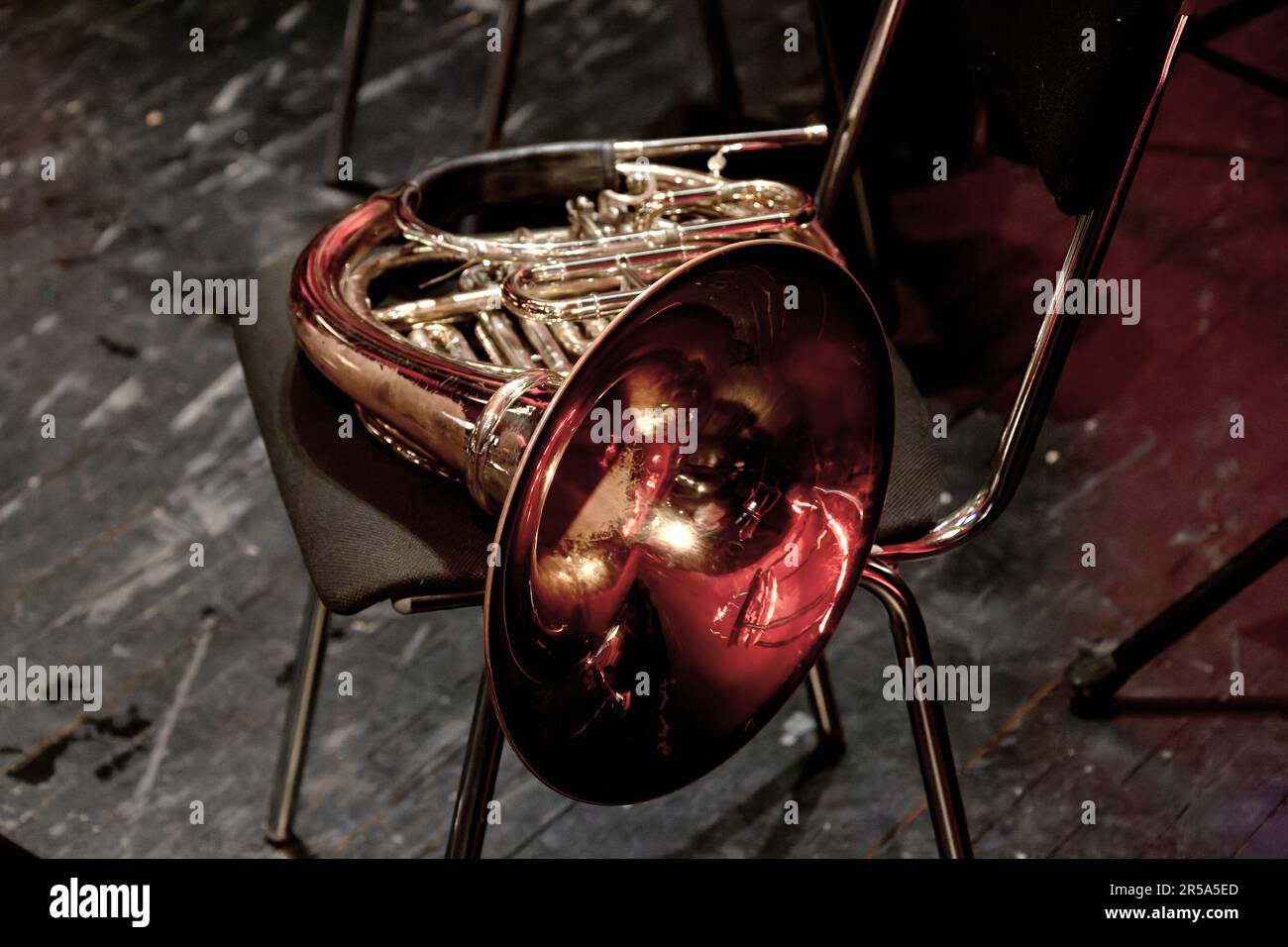 The image of a wind brass musical instrument horn lies on a chair in