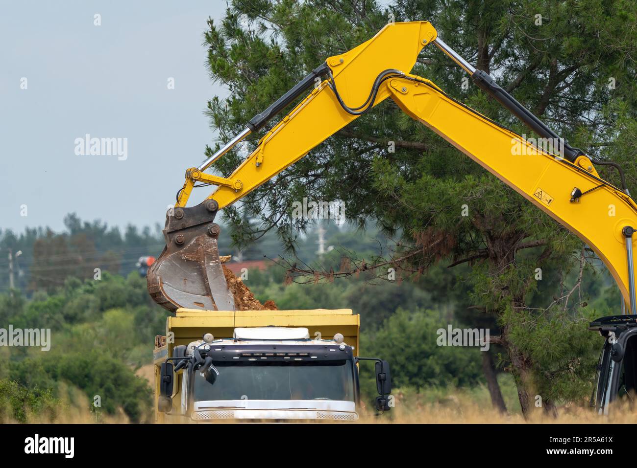 Digger loading soil onto a truck, earth loading bucket Stock Photo