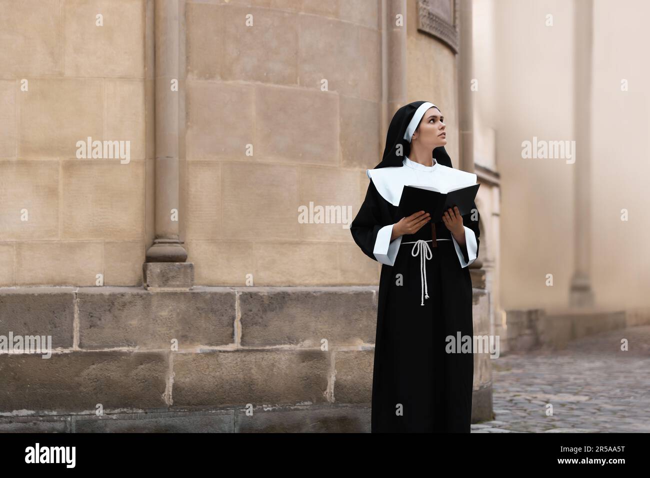 Young nun reading Bible near building outdoors Stock Photo - Alamy