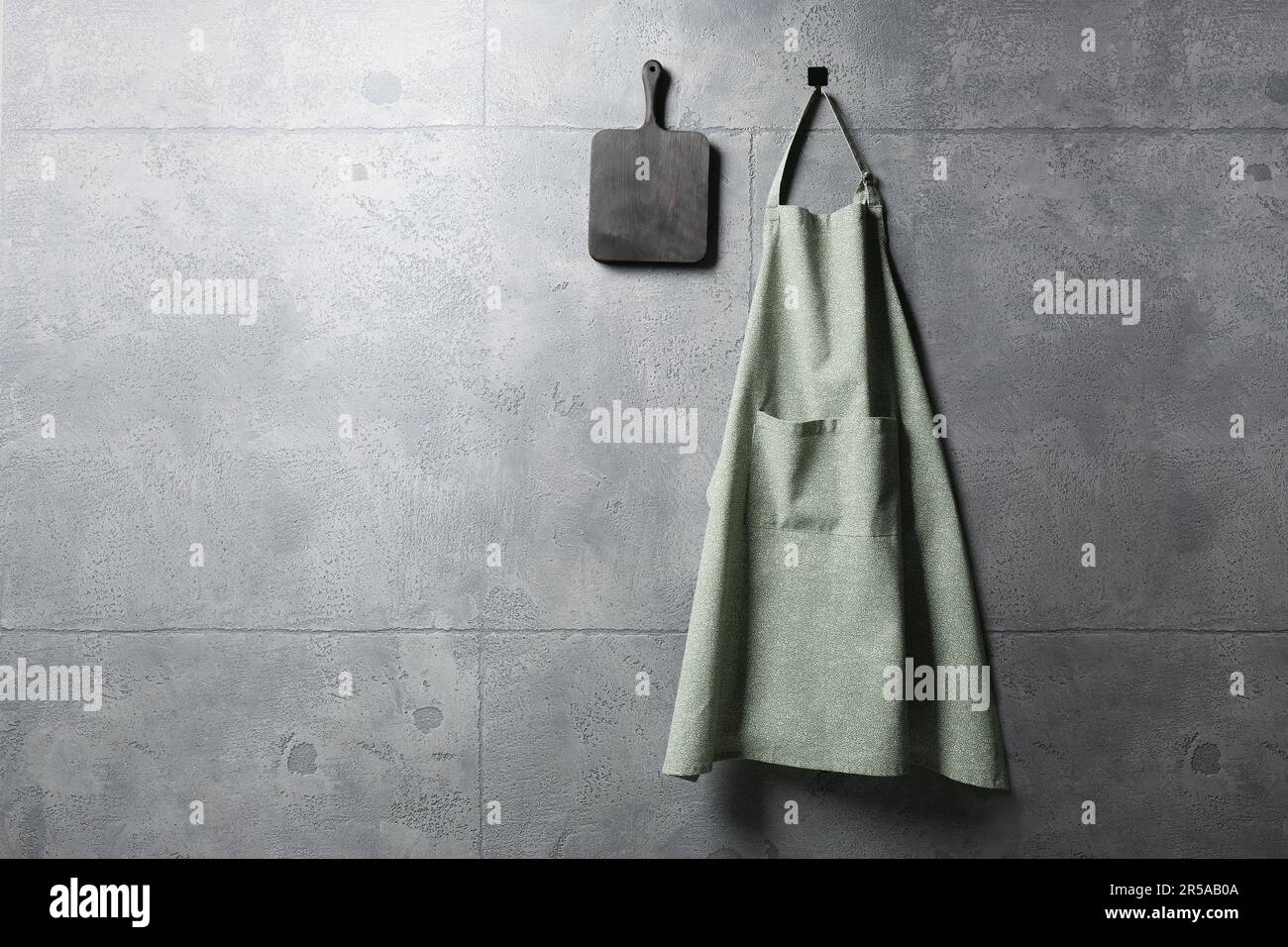 Clean kitchen apron with pattern and board on grey tiled wall. Space ...