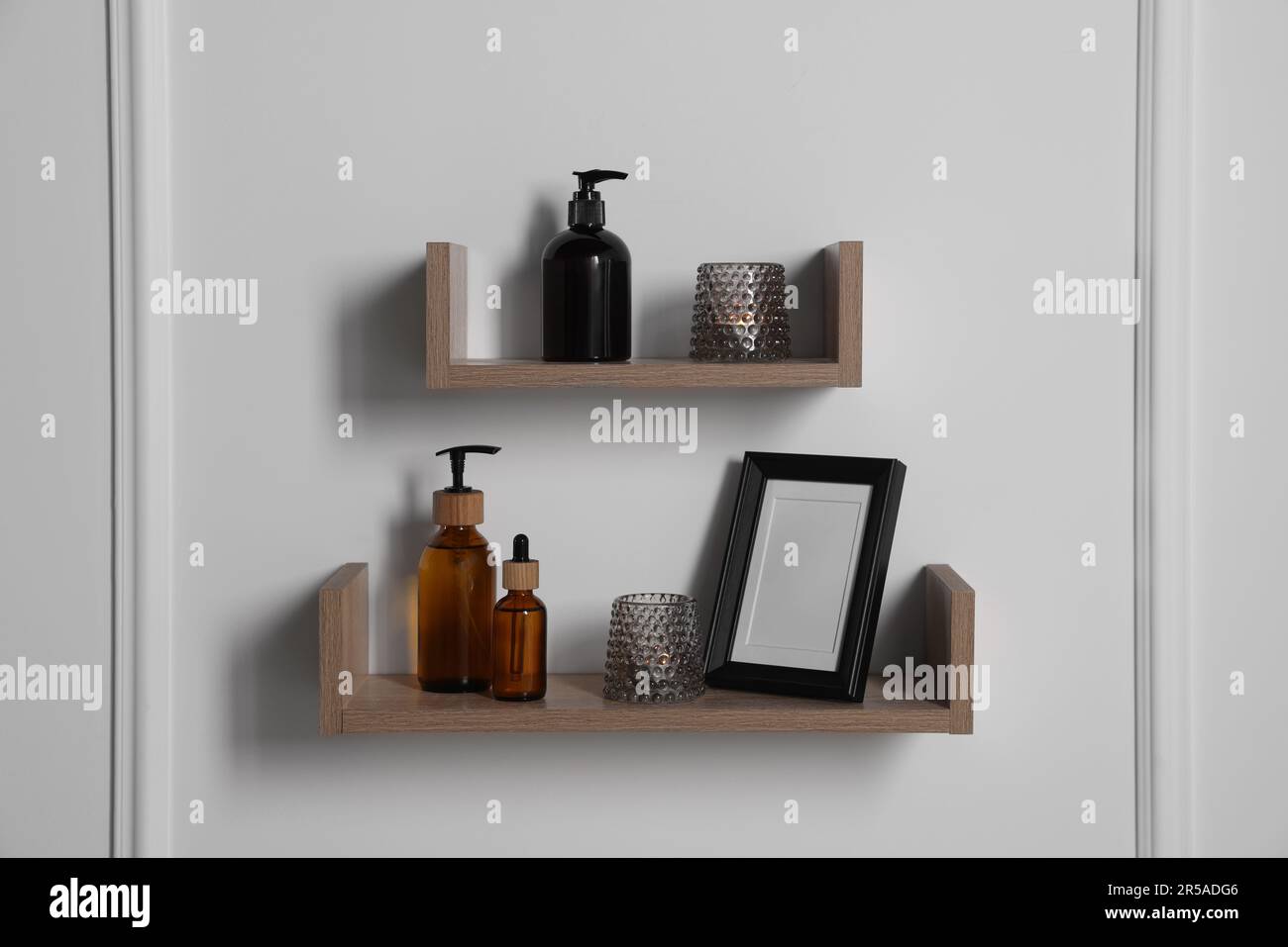 Wooden shelves with toiletries and decor on white wall. Interior design