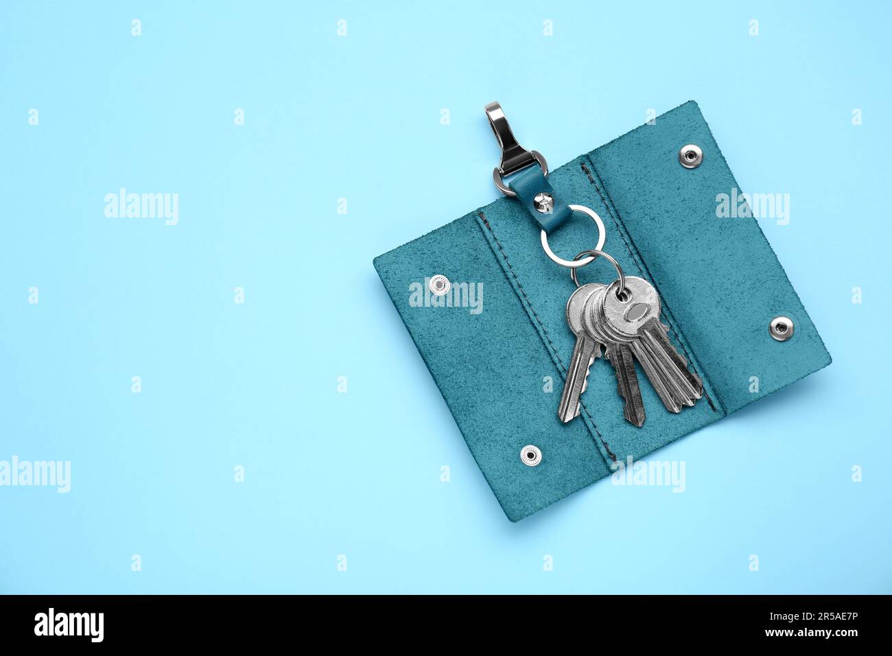 Leather holder with keys on light blue background, top view. Space for ...