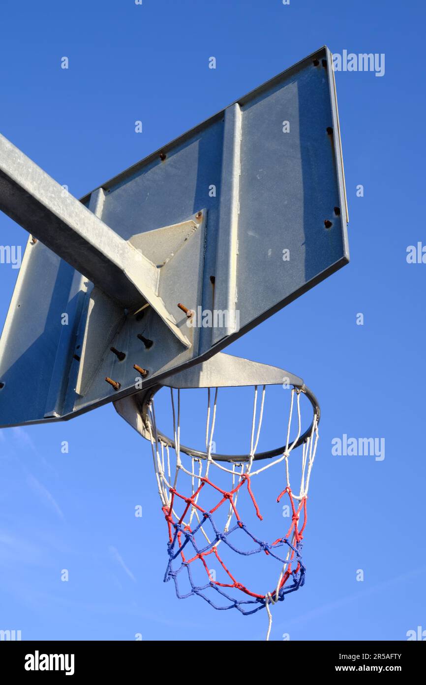 Low-angle view of a basketball hoop with a broken net Stock Photo