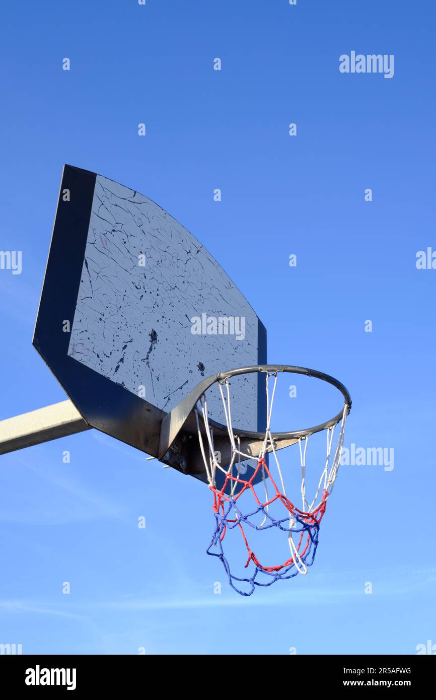 Low-angle view of a basketball hoop with a broken net Stock Photo