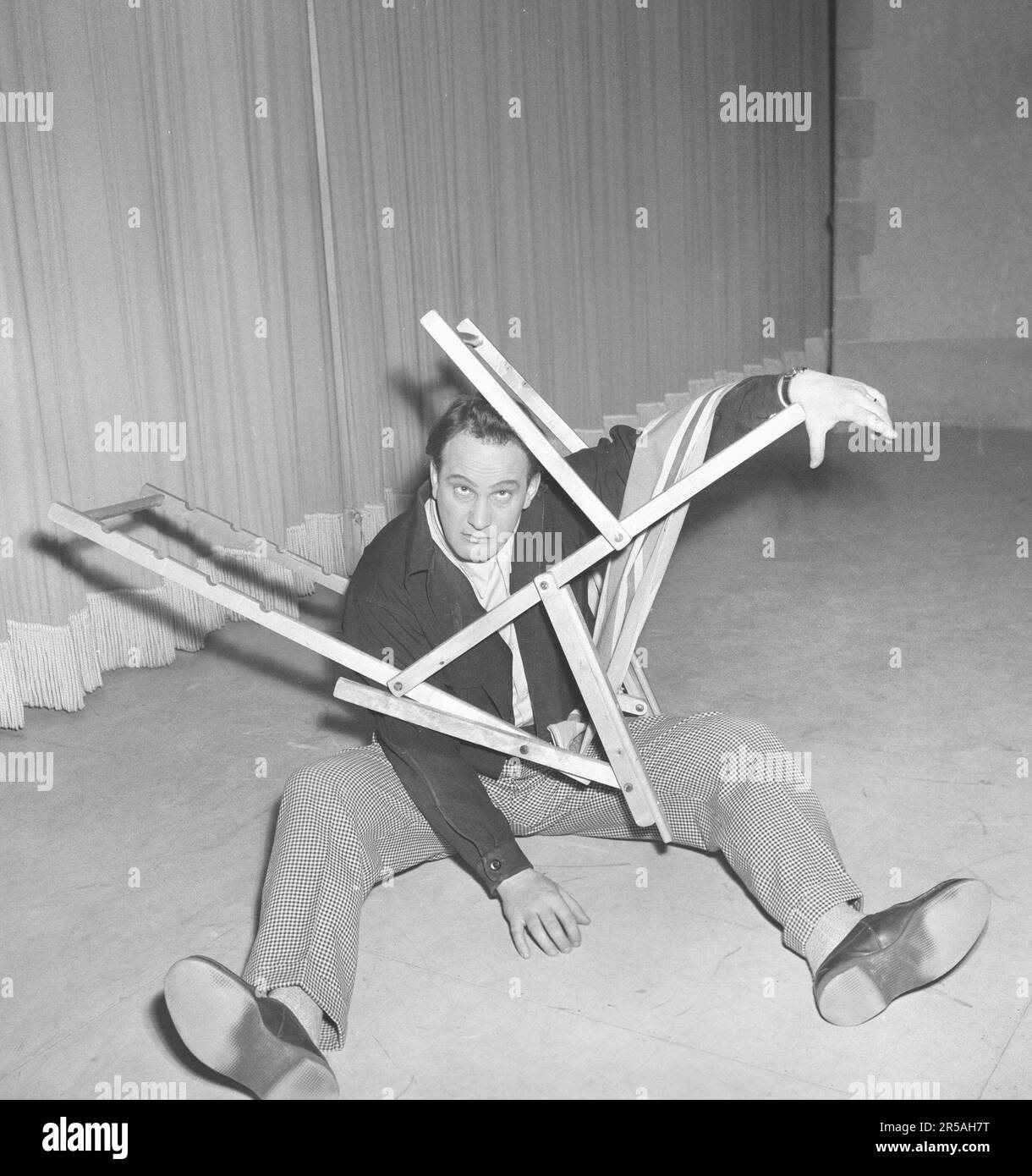 Carl-Gustaf Lindstedt , 1921-1992 , here in connection with a revue in the 1950s where in a classic sketch he tries to put together a deck chair the right way. Doesn't look like he's succeeding. The chair's construction, in its simplicity and genius, is something of a mystery to put together. Sweden 1953. Kristoffersson ref BK100-5 Stock Photo