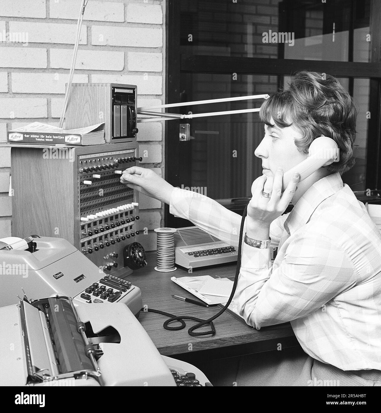 Telephony in the 1960s. Woman working at a telephone switchboard as it's operator. A telephone communication system that was manually operated where the incoming calls were forwarded and redirected to the another telephone number by the operator, in this case locally within the building serving a company or an organization with many internal telephone lines. The switchboard operator could take messages, put you on hold if the line was busy. Sweden 1965. Kristoffersson ref BM99-10 Stock Photo