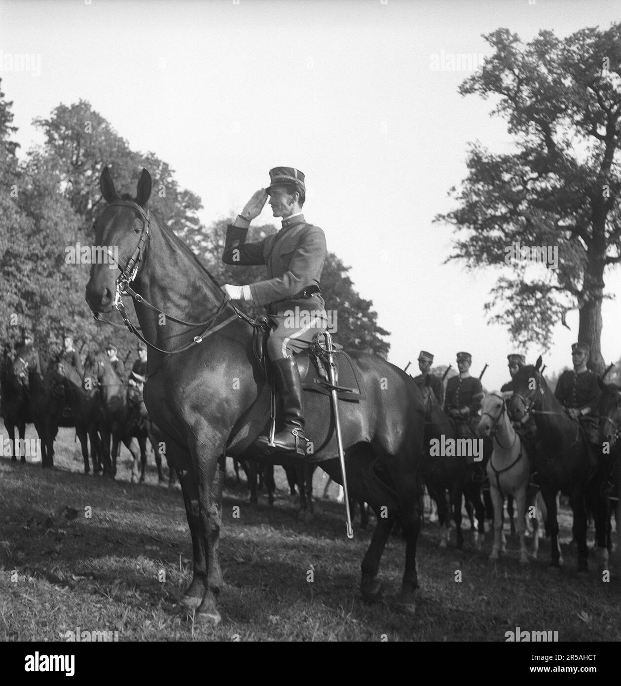 Swedish officer in the cavalry. Saluting while sitting on his horse with soldiers in line in the background.  At the time when the picture was taken, the Second World War was going on. Sweden mobilized soldiers and increased preparedness. On April 7, 1940, it was decided to start mobilizing the cavalry brigade. The main tasks of the cavalry are reconnaissance and rapid assault. In 1970 new acquisition of horses ceased.  Sweden in 1943. Kristoffersson ref F16-5 Stock Photo