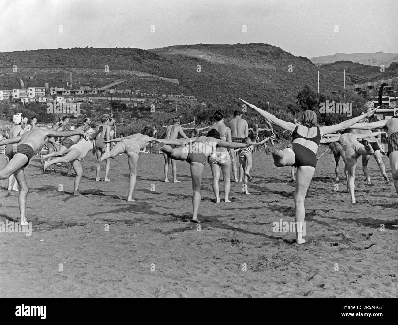 In the 1960s. A group of people are seen exercising on a beach on the Canary islands. There on holiday they join the activities like this one. 1965 Stock Photo