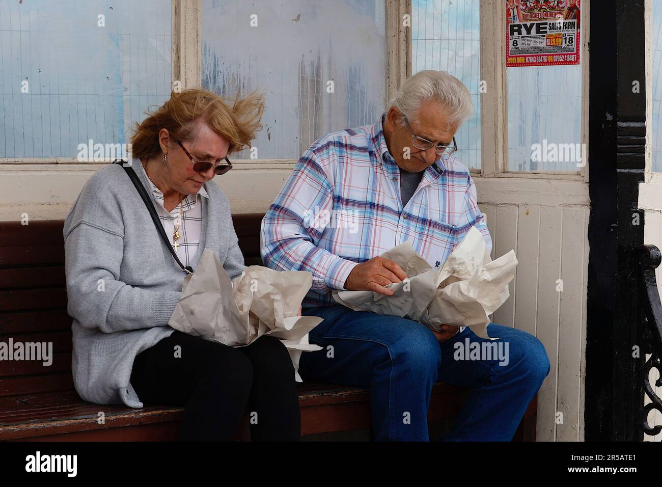 Hastings, East Sussex, UK. 02 June, 2023. Queues form outside Hastings fish and chip shops on Fryday. Celebrating fish and chips and the industry involved. Couple eating fish and chips in wrapped paper on a bench. Photo Credit: Paul Lawrenson /Alamy Live News Stock Photo