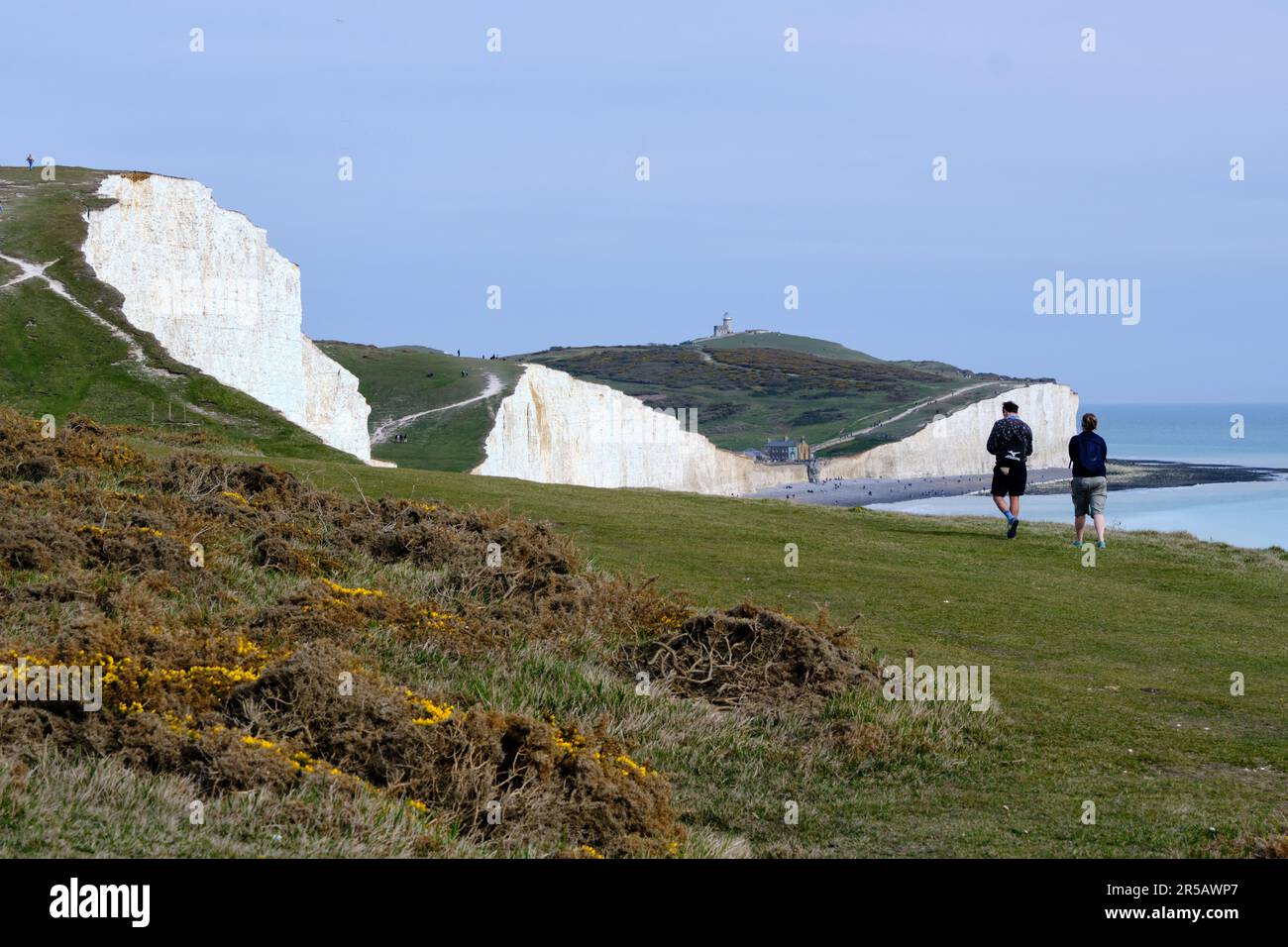 Couple walking along the white chalk cliffs, Seven Sisters National Park. Eastbourne, East Sussex, England Stock Photo