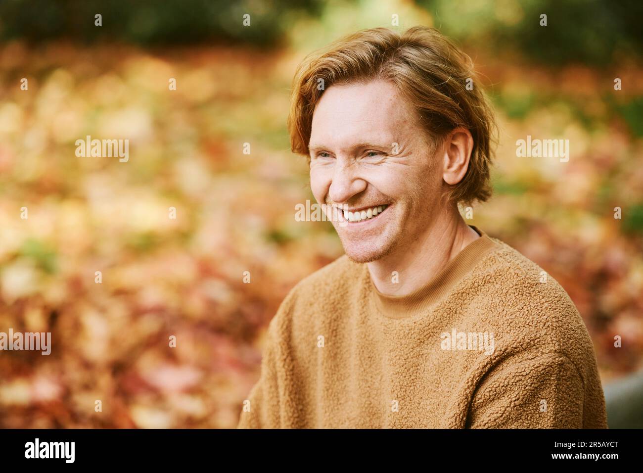 Close up portrait of handsome laughing red-haired man wearing  beige fuzzy fleece sweater Stock Photo