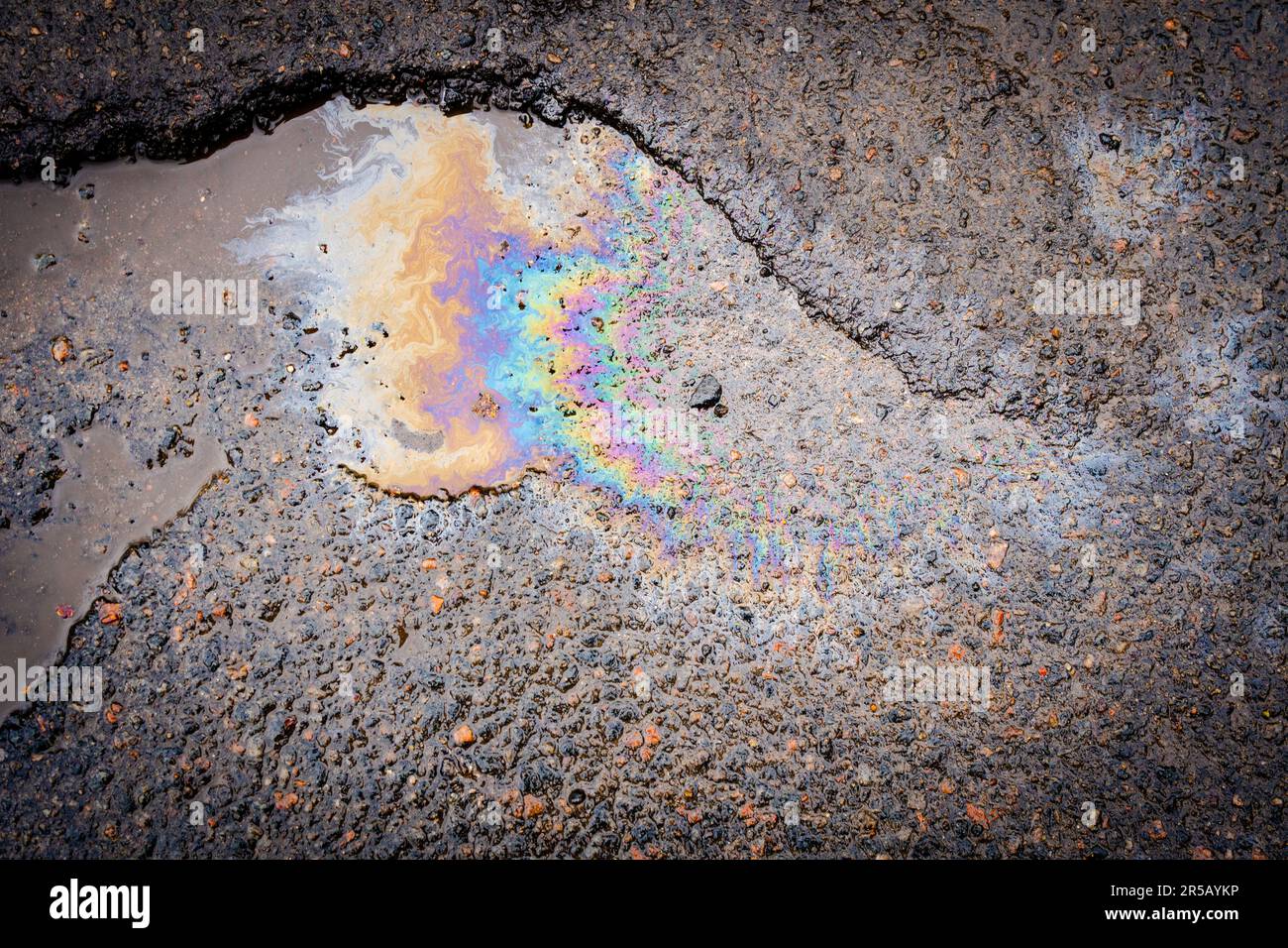 Colorful gas stain on wet asphalt. Oil stain caused by a leak under a car or truck Stock Photo