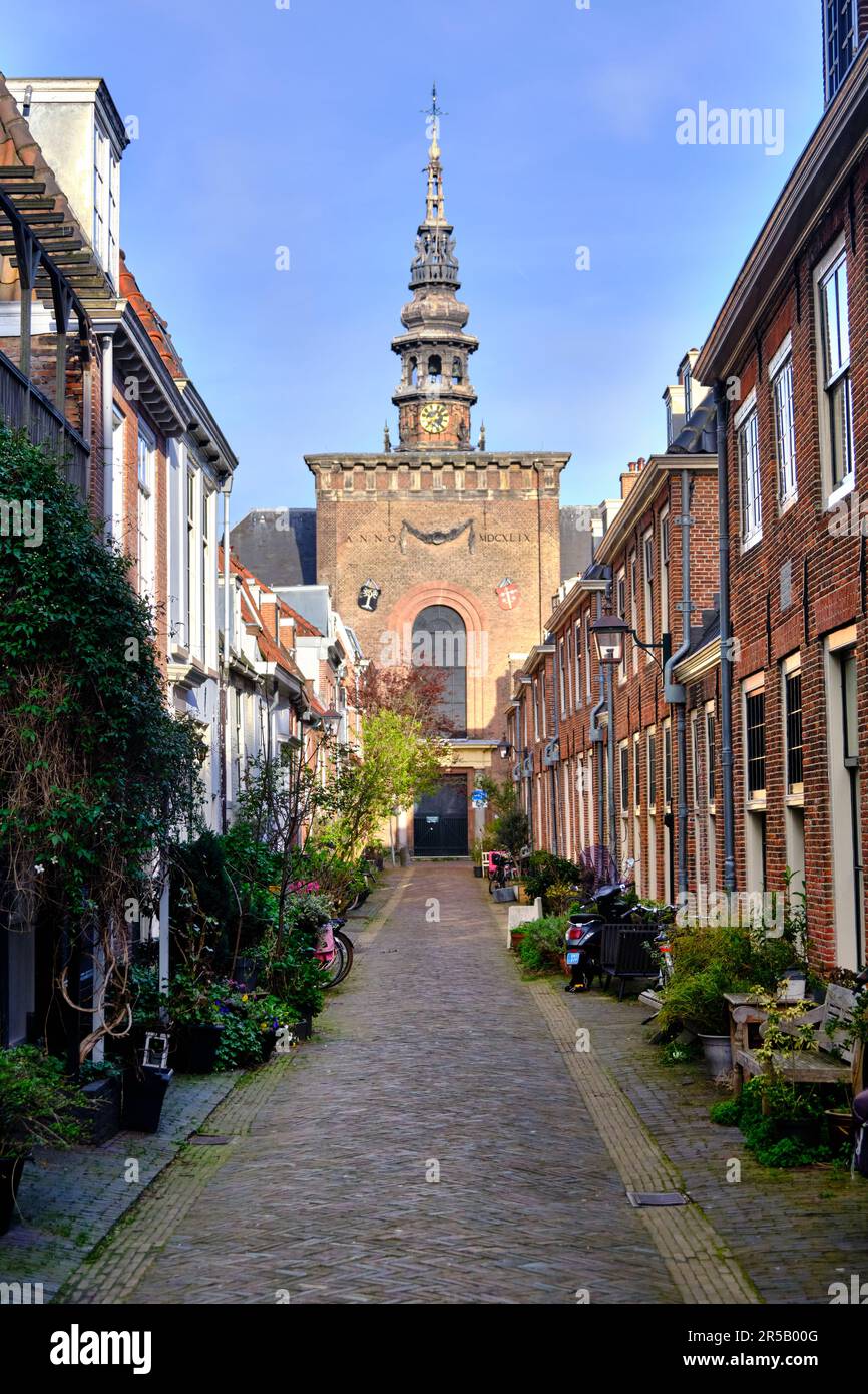 HAARLEM, NETHERLANDS - APRIL 12, 2022: A peaceful cobbled alley (Kerkstraat) with church tower and traditional houses. Stock Photo