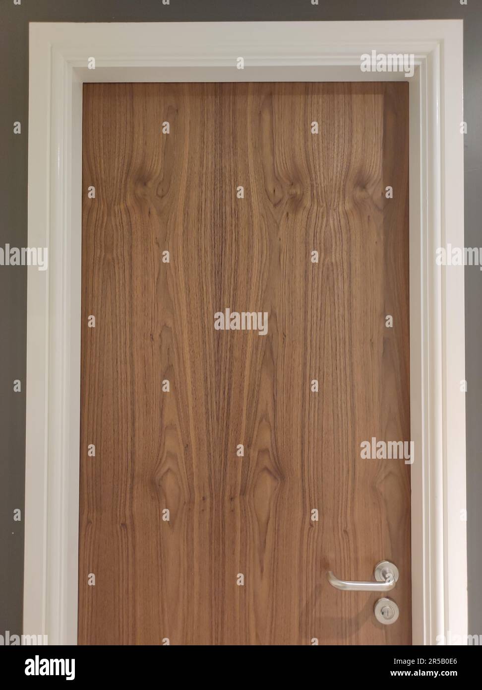 A brown wooden door with white frame in a beige room with a white ceiling Stock Photo