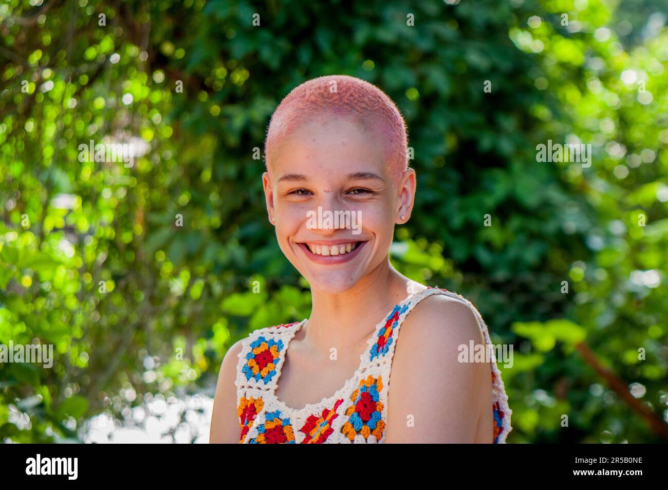 Portrait of a girl with very short hair, painted pink.Portrait of girl wearing crochet clothes. Stock Photo