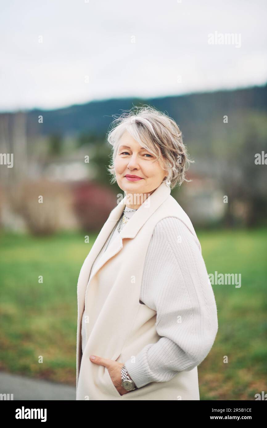 Outdoor portrait of beautiful middle age woman, wearing white coat Stock Photo