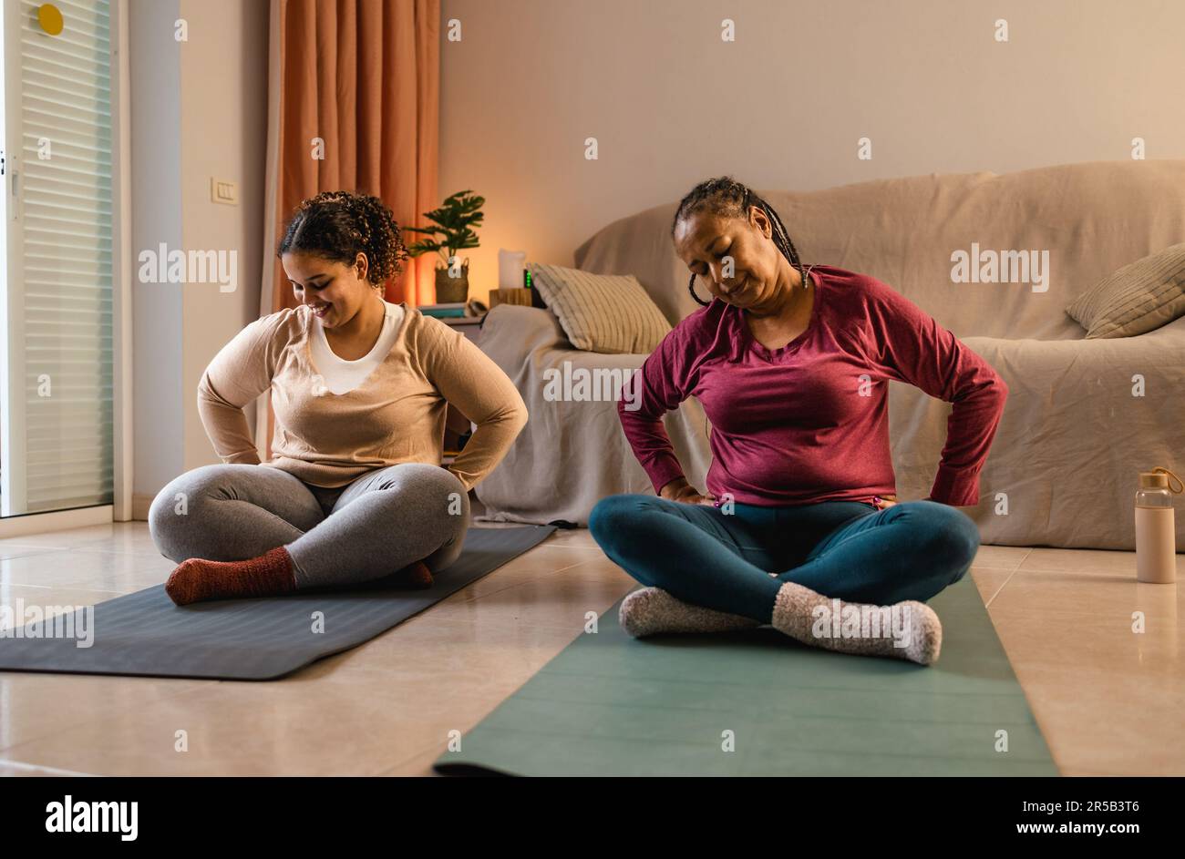 Happy African mother with her daughter doing yoga at home Stock Photo
