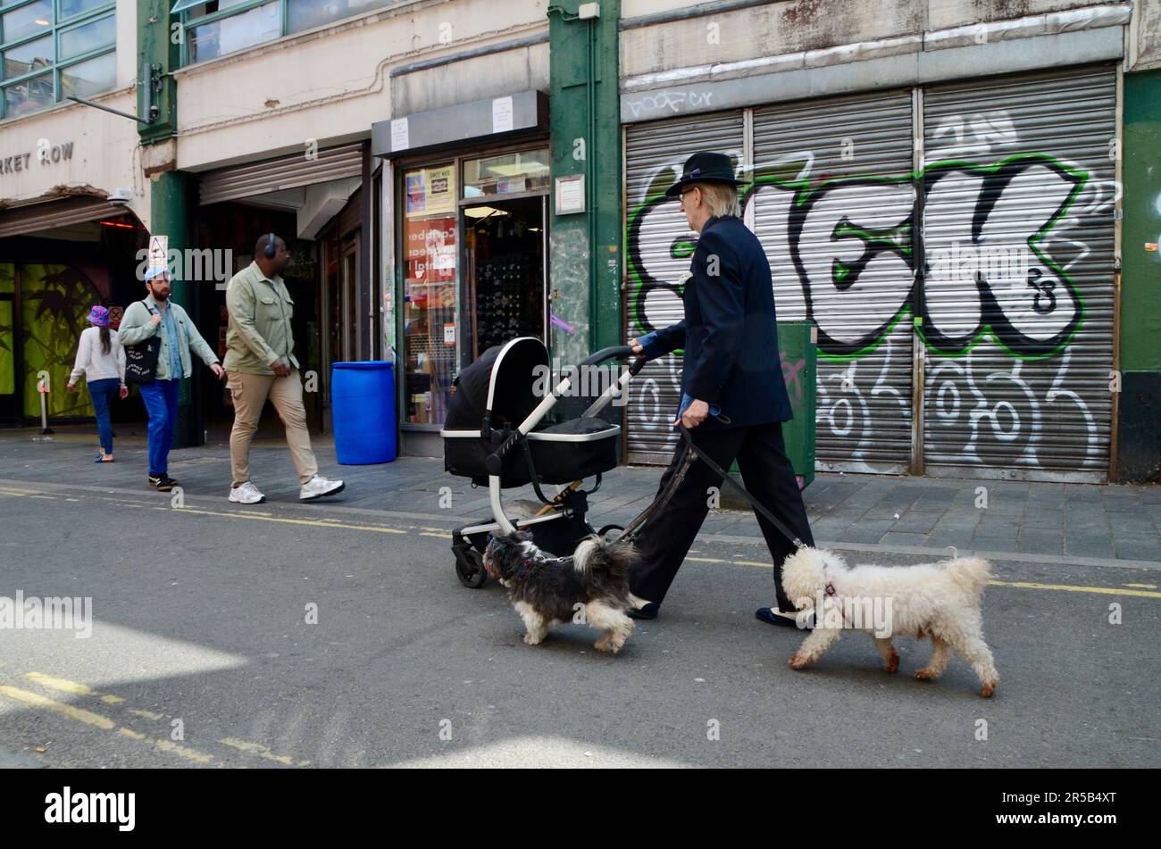 eccentric suited white man with dogs; brixton SW9 market with stalls shops restaurants bars etc in arcade and on street in lambeth london england great britain; brixton village market row and brixton village Stock Photo