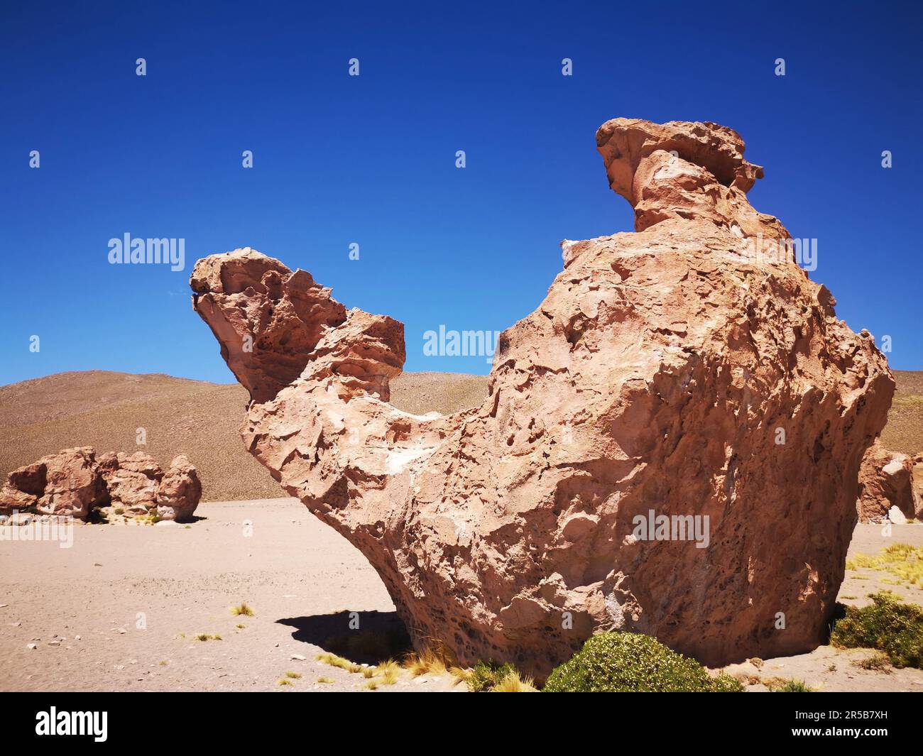 An isolated rock formation set against a backdrop of a deep blue sky, with no other signs of civilization nearby Stock Photo